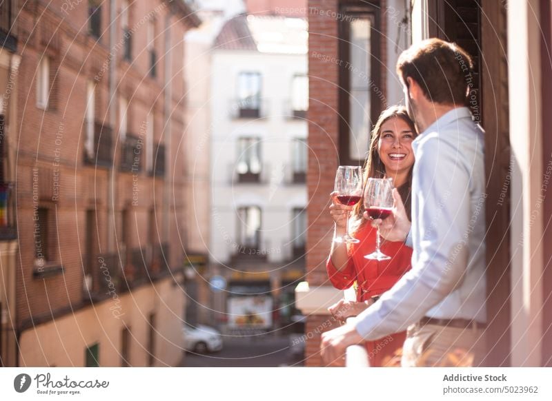 Happy couple with wine standing on balcony happy city cheerful glass young drink romantic together smile love relationship affection girlfriend boyfriend