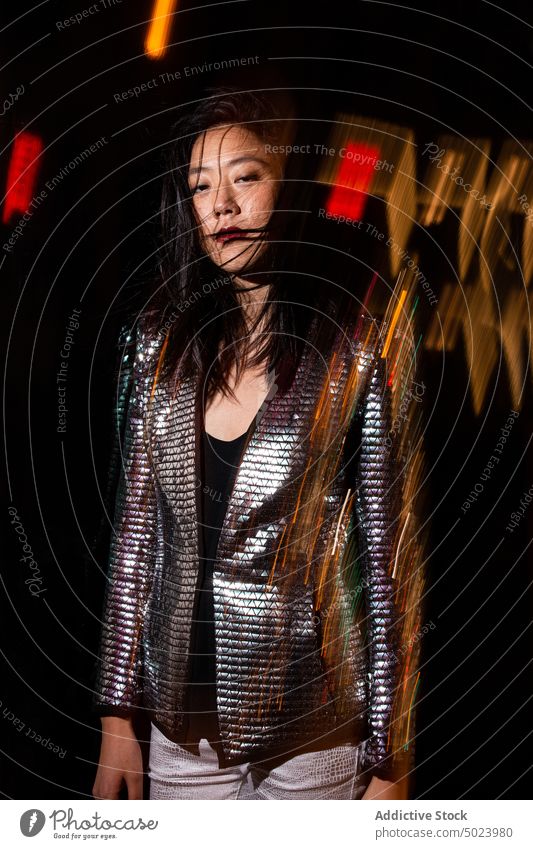 Stylish ethnic woman with messy hair at party night festive illuminate glow event confident nightlife dark female light glimmer shiny luminous celebrate young