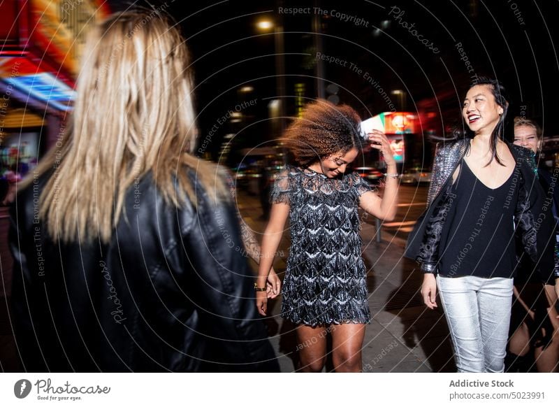 Diverse smiling friends walking on street at night women party cheerful style fun cool holiday gather happy celebrate event nightlife positive carefree leisure
