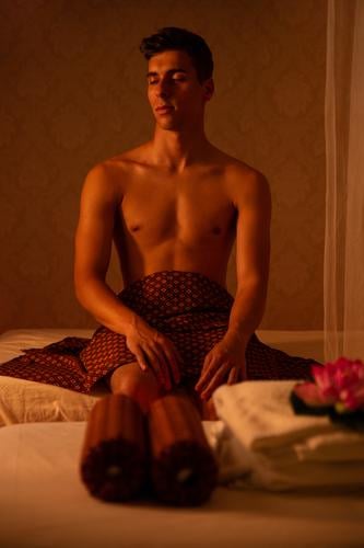 Athletic caucasian man sitting on bed of massage salon client closed eyes shirtless rest thai massage treatment therapy spa body wellness care beauty health