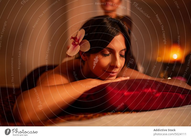 Attractive woman lying on bed of massage salon client caucasian closed eyes orchid shirtless rest thai massage treatment therapy spa body wellness care beauty