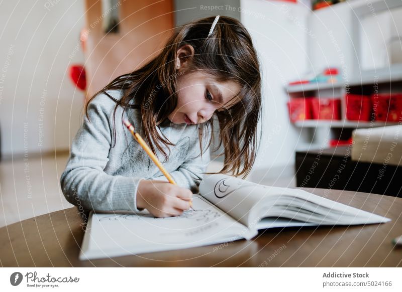 Concentrated girl drawing in coloring book kid album hobby talent skill childhood pencil table concentrate focus home little cute adorable pensive thoughtful