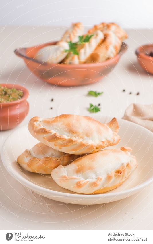 Delicious Argentinian empanadas in bowl with sauce chimichurri fried cuisine serve homemade food parsley allspice tasty meal delicious portion savory table