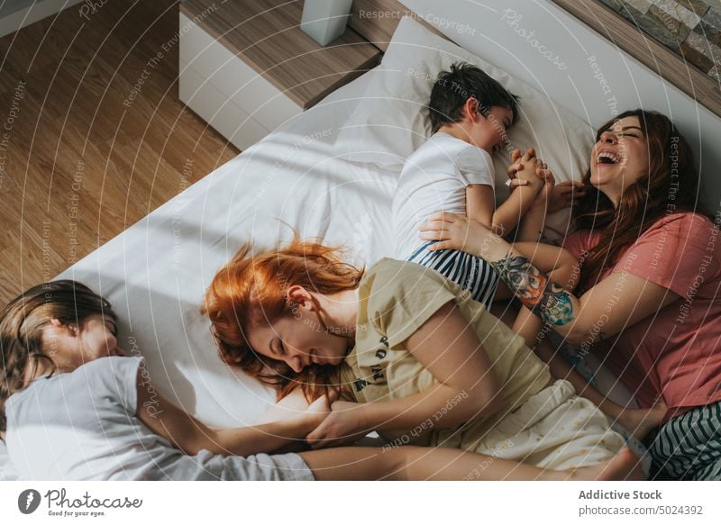 Smiling Women Sitting On Bed With Children bed bedroom indoors woman leisure alternative cheerful childhood children comfort cozy domestic female friendship