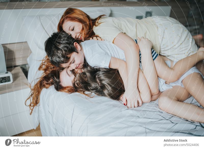 Smiling Women Sitting On Bed With Children indoors woman bed leisure bedroom comfort alternative cheerful childhood children cozy domestic female friendship