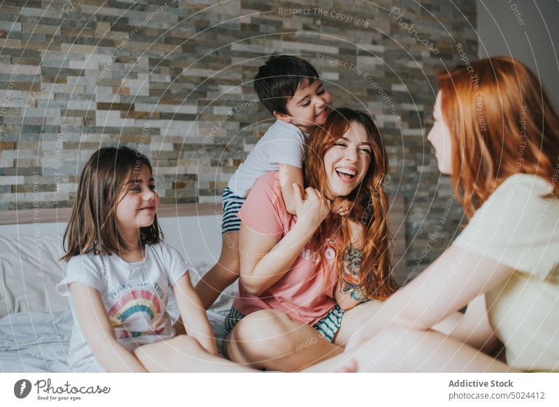 Smiling Women Sitting On Bed With Children woman friendship fun indoors laughing leisure alternative bed bedroom cheerful childhood children comfort cozy