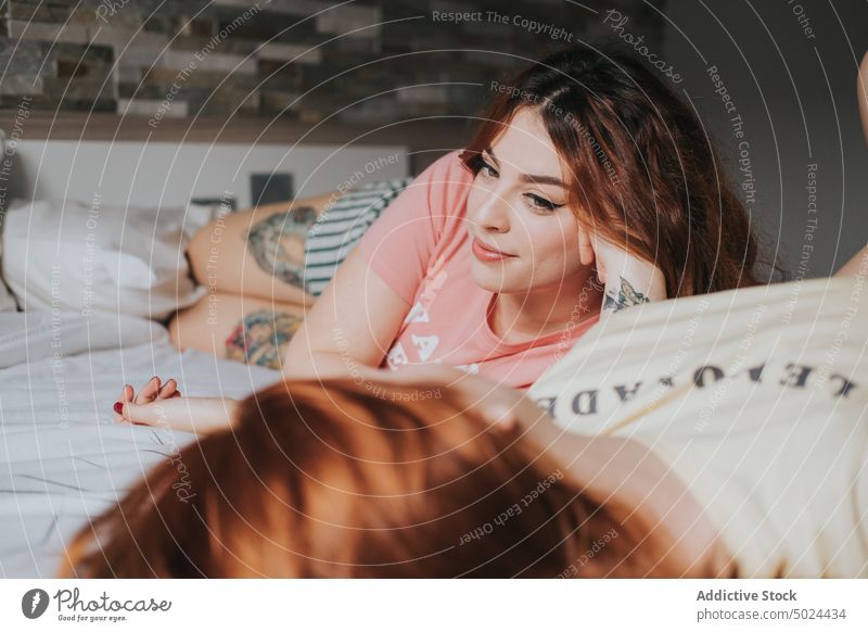 Women With Tattoos Resting On Bed indoors woman bed bedroom leisure young alternative art bedding comfort couple cozy female friend friendship fun gay