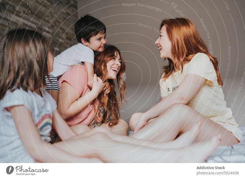 Smiling Women Sitting On Bed With Children woman indoors fun friendship alternative bed bedroom cheerful childhood children comfort cozy domestic female