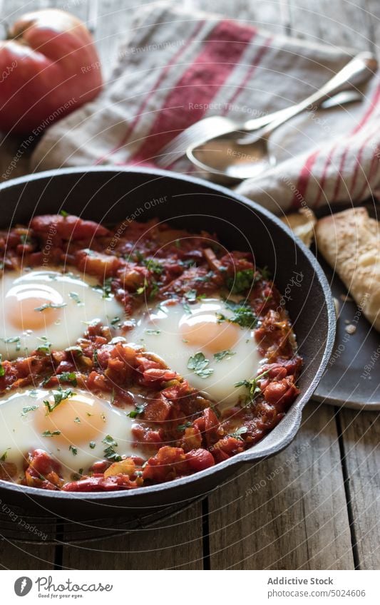 Frying pan with tomatoes and eggs shakshuka served delicious spicy fried sauce red wood breakfast food dish parsley rustic gourmet meal bread morning nutrition