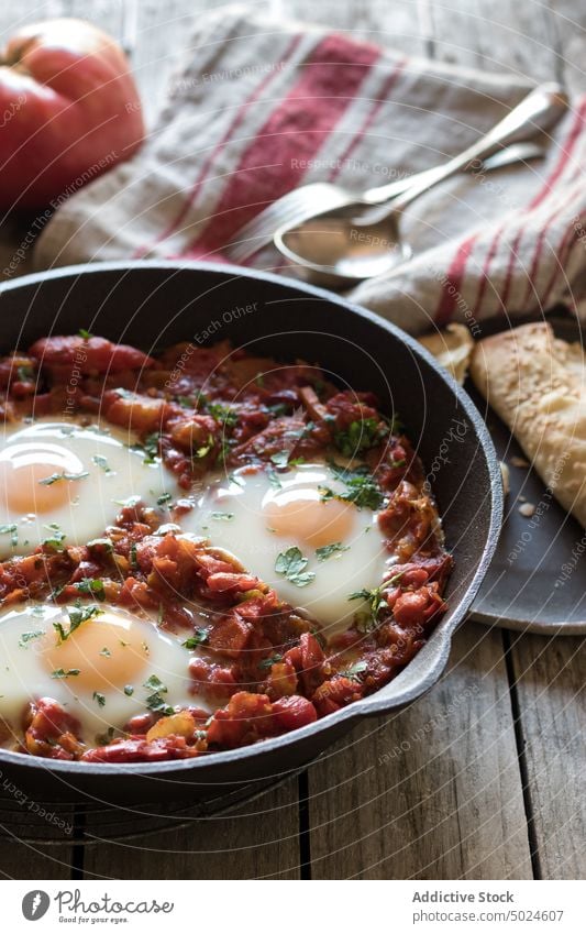 Frying pan with tomatoes and eggs shakshuka served delicious spicy fried sauce red wood breakfast food dish parsley rustic gourmet meal bread morning nutrition