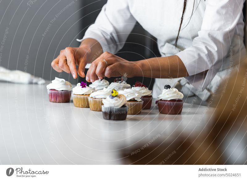 Crop woman decorating cupcakes on table in kitchen decorate baker bakery chef cook dessert vegan pastry female healthy tasty culinary treat sweet yummy berry