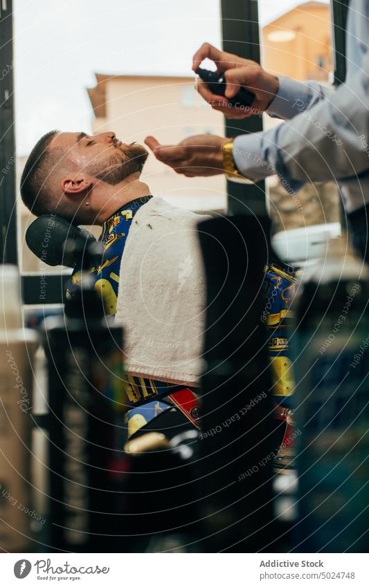 Barber working in a barbershop barber chair barber shop beard beauty care client clipper cut elegant haircut hairdresser hands head indoor lifestyle male man