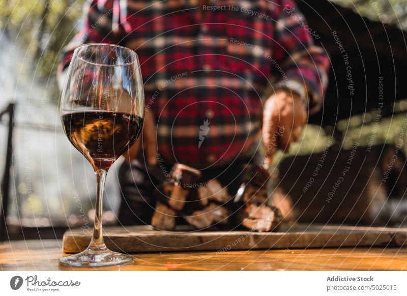 Crop man drinking wine against grilled meat pieces in garden food lunch beverage delicious prepare knife carving fork glass alcohol countryside checkered shirt