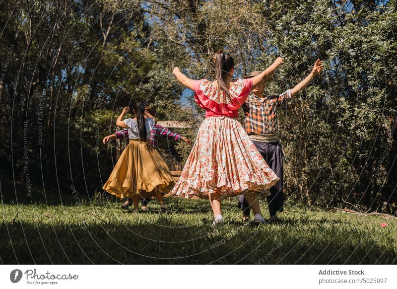 Unrecognizable ethnic friends dancing on lawn in garden dance folklore tradition culture active energy spend time women together people partner group skirt