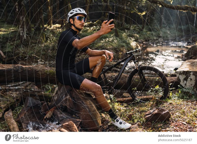 Unrecognizable cyclist taking photo of river on smartphone in forest take photo nature sport trip man using gadget creek bicycle environment helmet protective