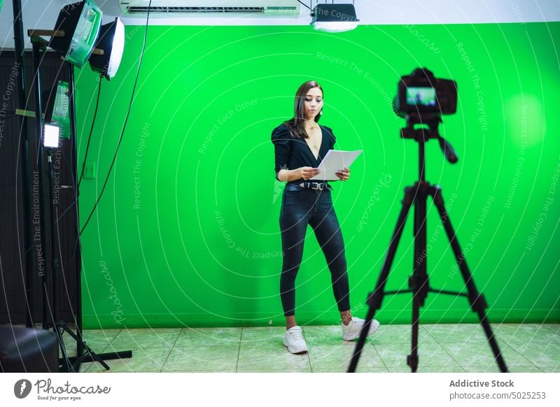 Woman reading text on paper while filming video woman blogger record social media document prepare news female influencer gadget professional connection serious
