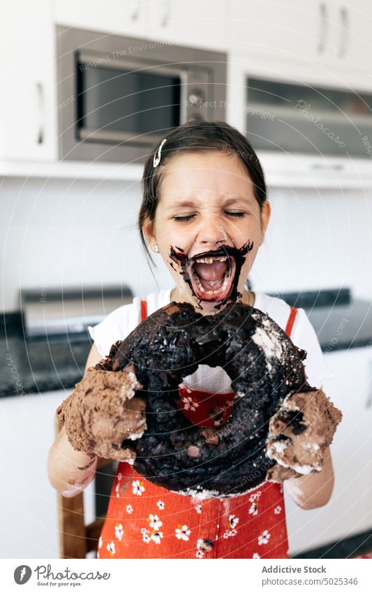 Funny girl with delicious chocolate cake at home mouth opened hungry having fun treat tasty childhood kitchen eyes closed sweet glaze culinary homemade baked