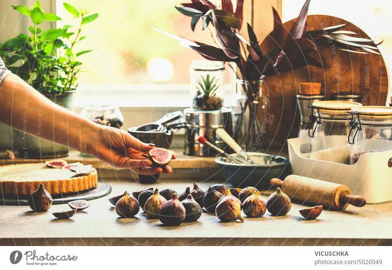 Women hand holding figs on kitchen table with baking tools at window  background. Lifestyle - a Royalty Free Stock Photo from Photocase