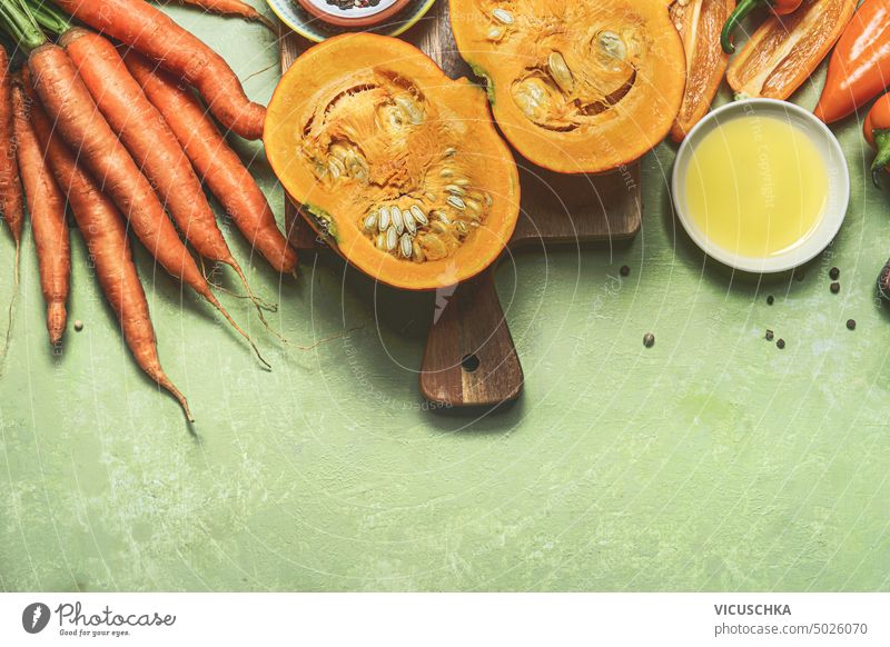 Orange colored vegetables: pumpkin, carrots , and paprika on kitchen table with cooking ingredients, banner. Top view orange top view vegan home cooking