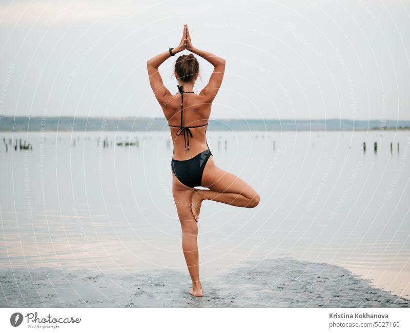 Young woman practicing yoga in water estuary, lake or river. Asana