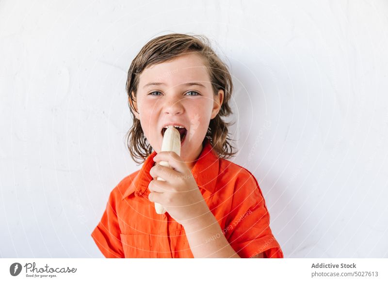 Adorable hungry kid eating banana against white background girl child fruit smile happy healthy food positive portrait cheerful yummy sweet delicious female