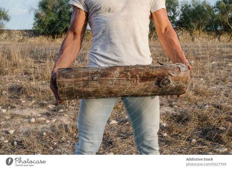 Strong male farmer with log man work countryside carry agriculture strong daytime adult casual worker agronomy job t shirt jeans weather nature season cloudy