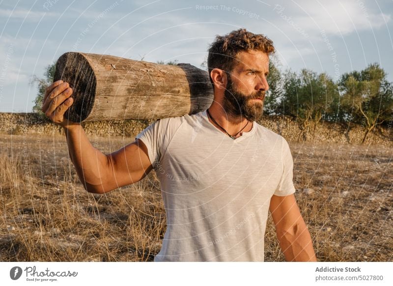 Strong male farmer with log man work countryside carry agriculture strong daytime adult casual worker agronomy beard job t shirt jeans weather nature season