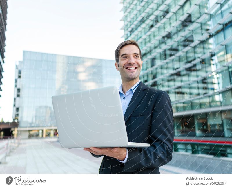 Businessman browsing netbook near modern building businessman entrepreneur laptop using work executive surfing computer pensive male employee elegant think job