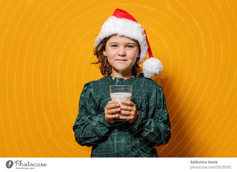 Girl in Santa hat drinking milk girl christmas celebrate glass tradition holiday colorful bright santa hat event xmas kid cheerful smile season happy adorable