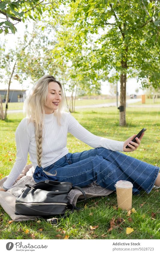 Happy woman taking selfie in park take smartphone lawn smile style urban female mobile glad optimist beverage takeaway positive to go lifestyle grass drink