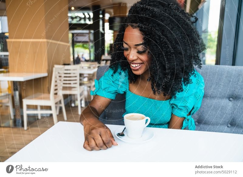 Black woman with coffee in cafeteria smile table chill cheerful coffee shop hot drink restaurant glad content makeup beverage female charming delight sit black
