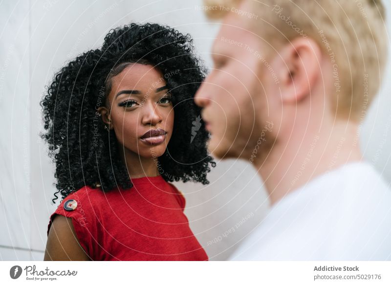 Serious multiethnic couple standing opposite each other near wall boyfriend girlfriend unemotional serious afro makeup against appearance relationship pensive