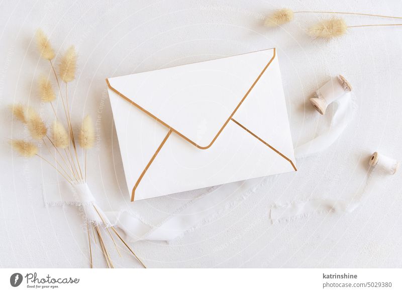 Blank envelope near silk ribbons and dried hare's tail grass top view on white, boho mockup bohemian wedding hare tail grss beige romantic natural copy space