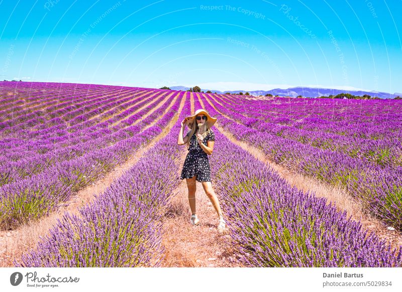 Close up of a young girl in a floral dress with a hat on her head between lavender in southern Provence Valensole France woman sunny summer spring smile purple