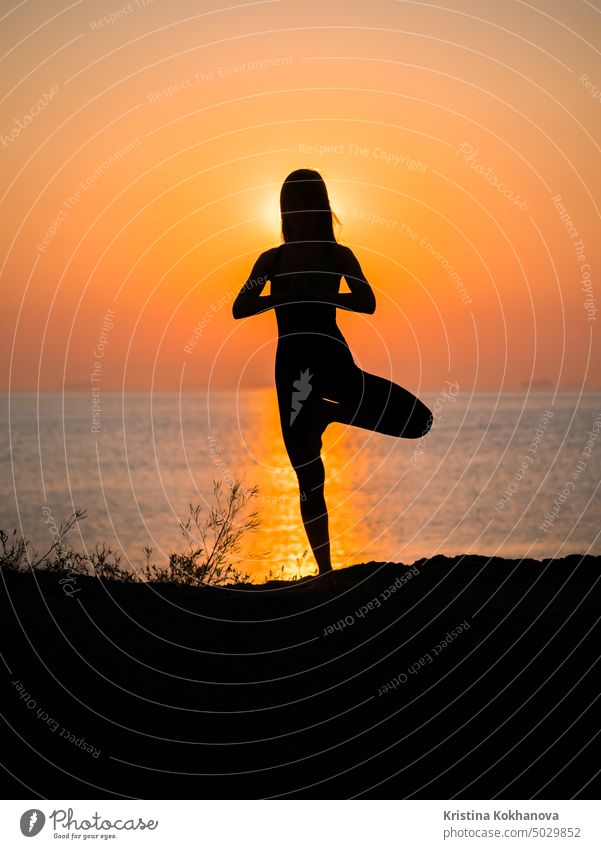 Silhouette young woman practicing yoga on the beach above sea at amazing sunset. fitness, sport, yoga and healthy lifestyle concept nature sunrise body energy