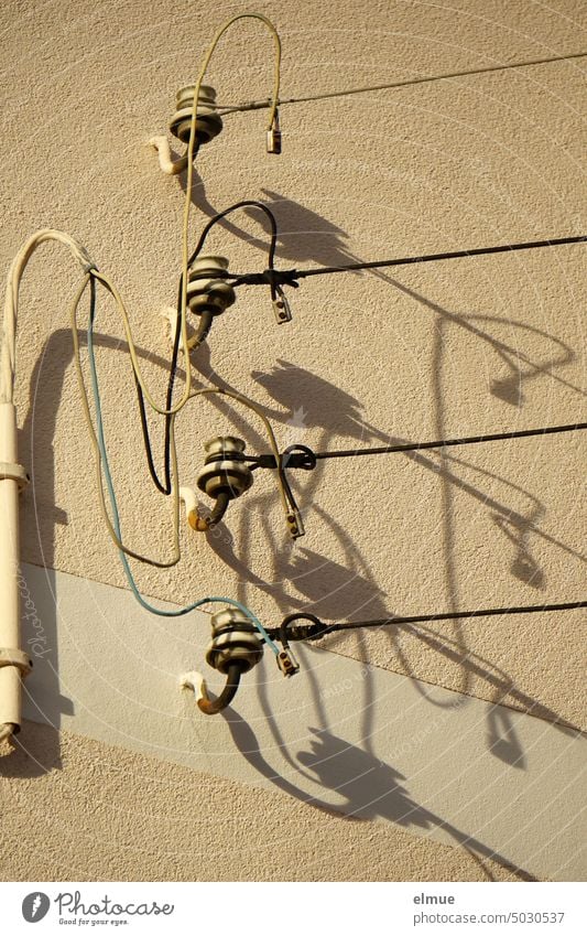 Four power insulators with connected overhead lines on a house wall, casting shadows Insulator Current insulators Porcelain insulators power line Shadow play