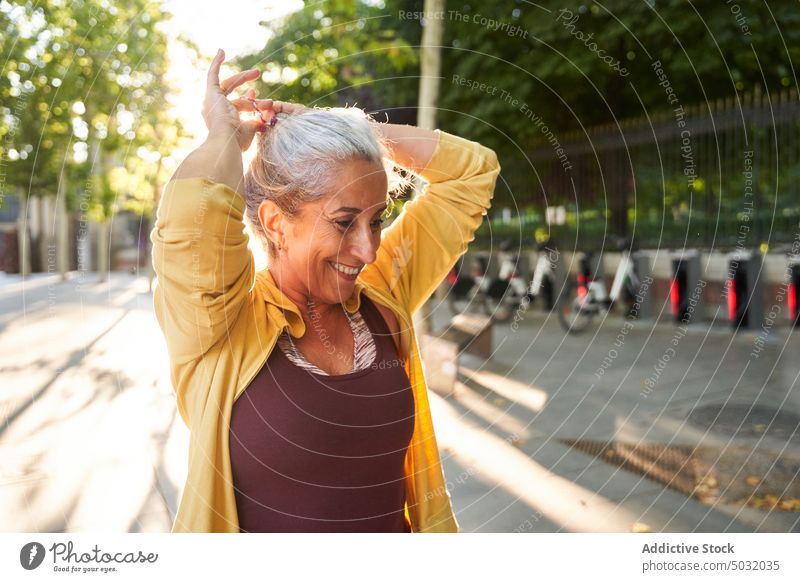 Glad elderly sportswoman doing hair smile ponytail tie fitness training street morning prepare happy female aged senior workout vitality athlete activity retire