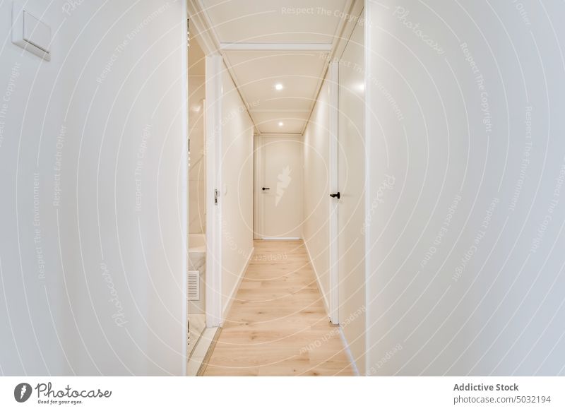 Hallway with white walls and laminated floor in flat corridor apartment interior door hallway spacious residential entrance style modern property contemporary