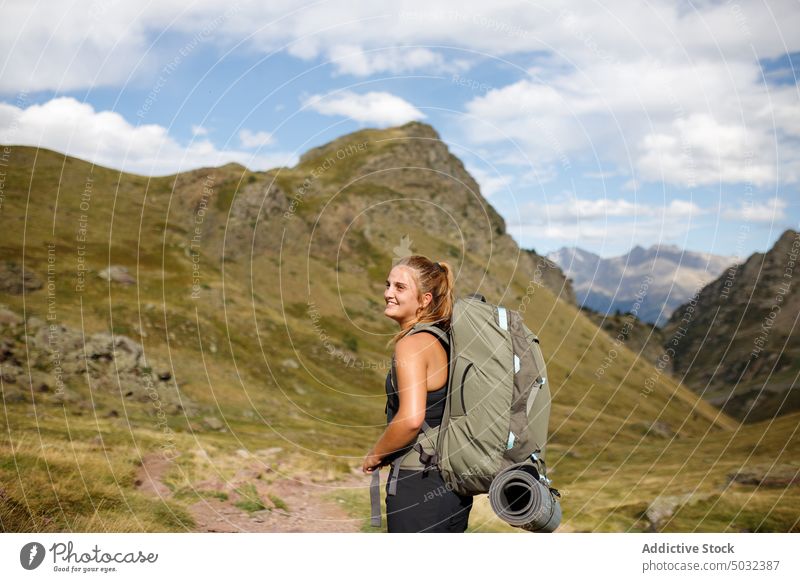 Cheerful female traveler in mountains woman smile trekking happy hike backpack summer mat countryside tourism young trip blue sky cloudy nature activity