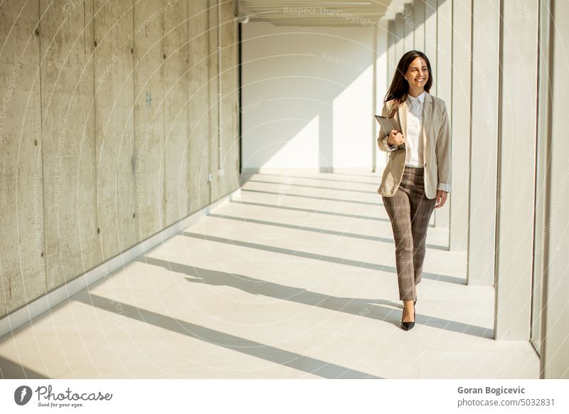 Young businesswoman walking on modern office hallway adult attractive beauty brunette business person businesspeople businessperson caucasian cheerful content
