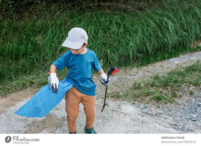 Boy cleaning garbage in countryside volunteer collect plastic trash pollute pick boy environment nature ecology waste recycle rubbish litter participate