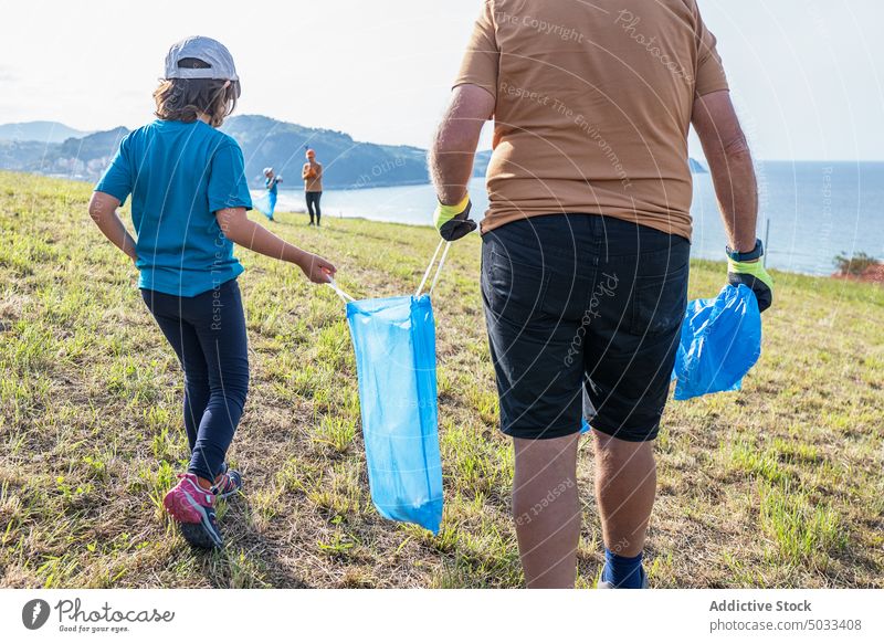 Group of volunteers picking garbage on shore near sea people girl grandfather mother boy group trash collect nature eco friendly environment hill recycle