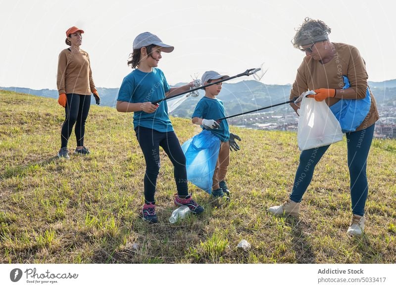 Volunteers collecting trash on grassy meadow in nature volunteer garbage environment rubbish woman grandmother children ecology countryside litter pollute waste