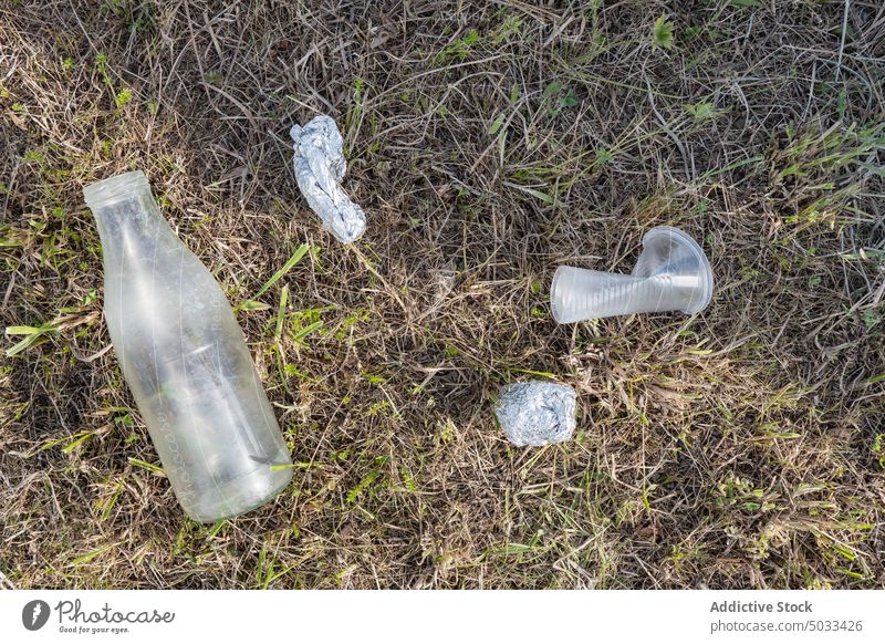 Plastic trash left on grassy ground waste plastic bottle cup foil pollute used meadow rubbish environment container ecology nature litter garbage disposable