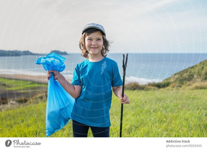 Preteen volunteer standing on field with trash bag kid girl garbage bin environment sea ecology plastic rubbish waste nature cap litter collect recycle summer