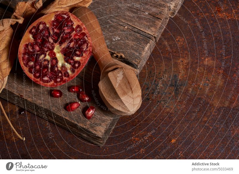 Ripe pomegranate on wooden board ripe fruit dark seed arrangement fresh healthy food gourmet meal natural organic whole color nutrition squeezer chopping board