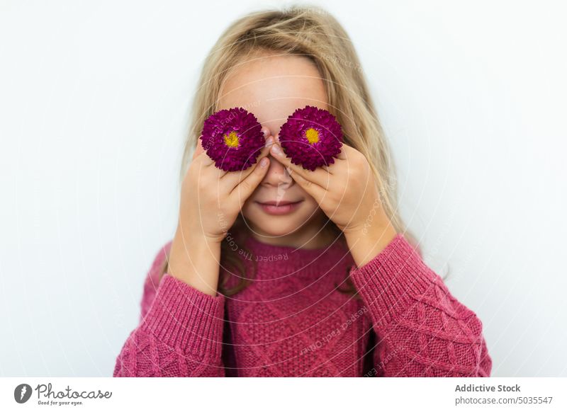 Girl covering eyes with blooming flowers girl portrait smile child cover eyes positive sweater purple blond happy kid cheerful preteen glad joy shy warm
