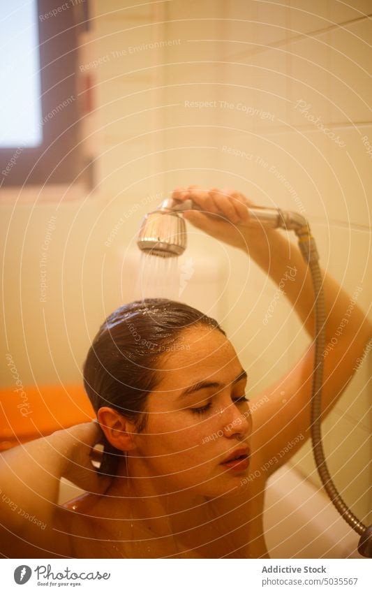 Young lady washing hair in shower woman shower head pour wet hair clean water hygiene bathroom pure tranquil female sensual touch hair peaceful bathtub