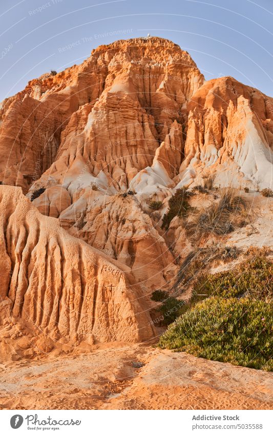 Cliffs against cloudless sky in summer cliff blue sky beach sand formation rock sandstone daytime arid rough falesia algrave portugal ridge scenery desert