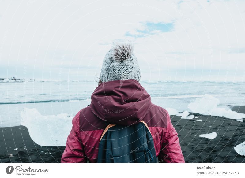 Photo from behind of a woman in front of a glacier in iceland, winter travel, cold weather concept. mountain journey happiness people hiking adventure beauty